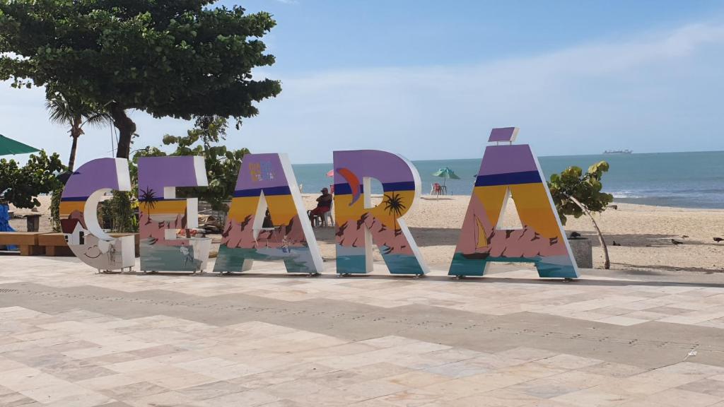 un panneau sur la plage avec l'océan en arrière-plan dans l'établissement APTO LUXO EM HOTEL - BEIRA MAR FORTALEZA, à Fortaleza