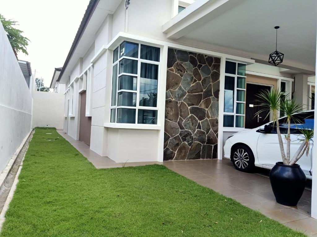 a white car parked in front of a house at Permata Hanan Homestay Sungai Petani Kedah in Kampong Pinang