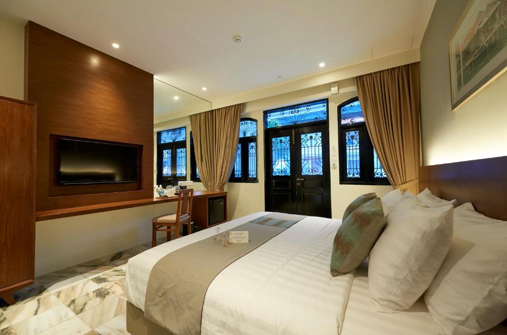 Macalister Terraces Hotel في جورج تاون: غرفة نوم بسرير كبير وتلفزيون