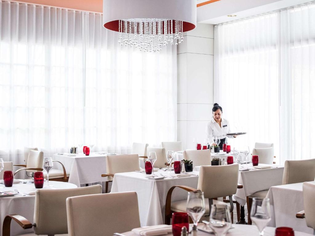 a woman standing in a dining room with tables at Pullman Miami Airport in Miami