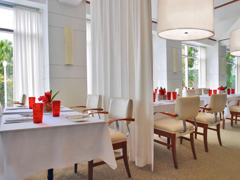 a dining room with white tables and chairs at Pullman Miami Airport in Miami