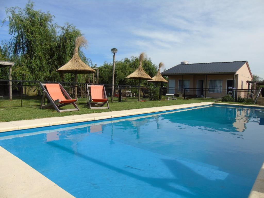 a swimming pool with two chairs and umbrellas at Aitue Bungalows in Gualeguaychú