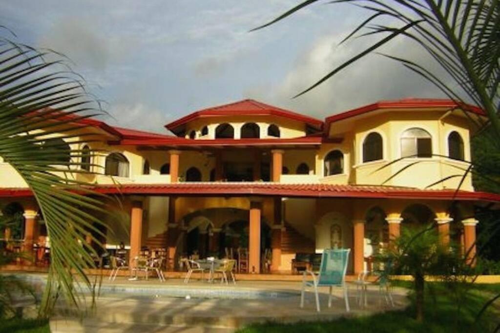 a large house with tables and chairs in front of it at Villa Los Aires Costa Rica in Caña Blanca