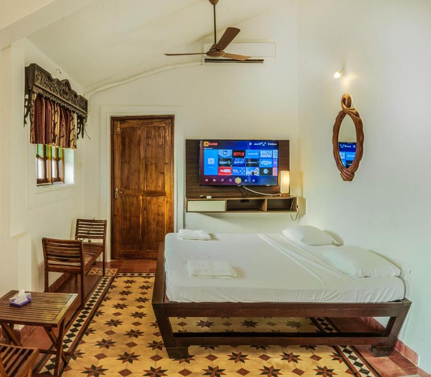 a bedroom with a bed and a flat screen tv at O Abrigo in Panaji