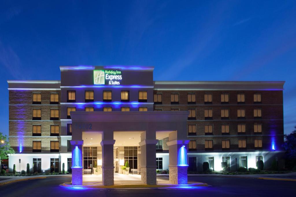 Holiday Inn Express & Suites Laurel Lakes, an IHG Hotel في لاوريل: مبنى الفندق والاضائه الزرقاء امامه