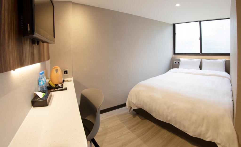 a bedroom with a white bed and a window at Alishan Shermuh Tourist Hotel in Zhongzheng