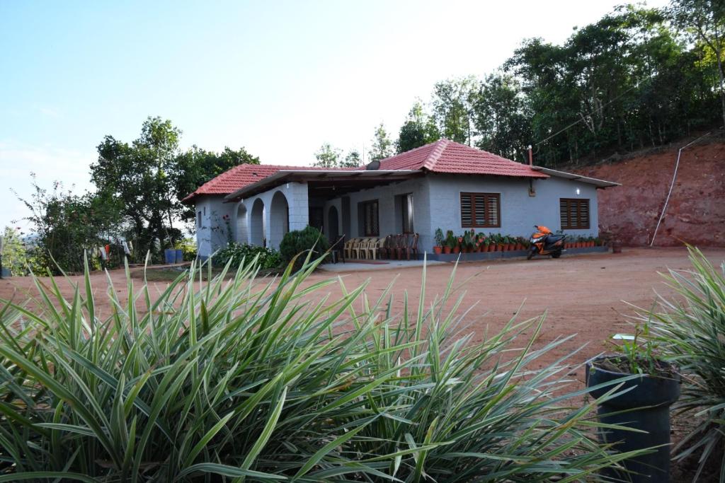 a small white house with a red roof at Nature INN Homestay - Hill Top Mountain View & River Access in Sakleshpur