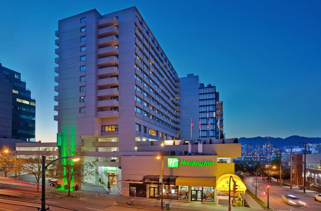 un edificio alto en una calle de la ciudad por la noche en Holiday Inn Vancouver-Centre Broadway, an IHG Hotel en Vancouver