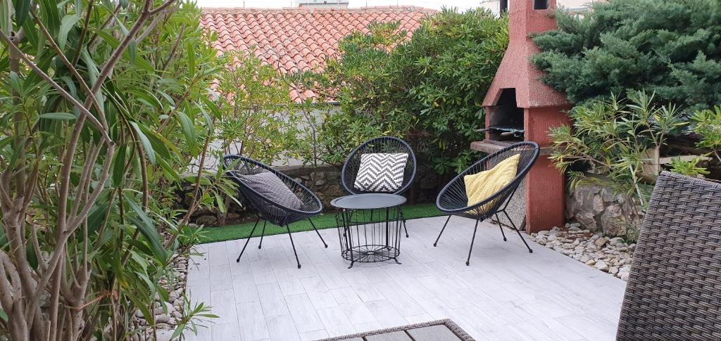 trzy czarne krzesła i stół na patio w obiekcie Green Garden Gajac Apartman w mieście Skunca