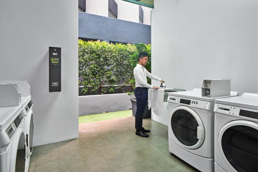 a man standing in a kitchen with a washing machine at Holiday Inn Express Singapore Orchard Road, an IHG Hotel in Singapore