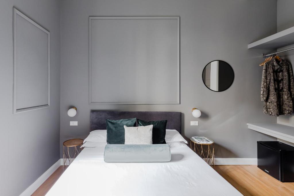 Un dormitorio con una gran cama blanca con almohadas verdes. en Suites by Chloe, en Roma
