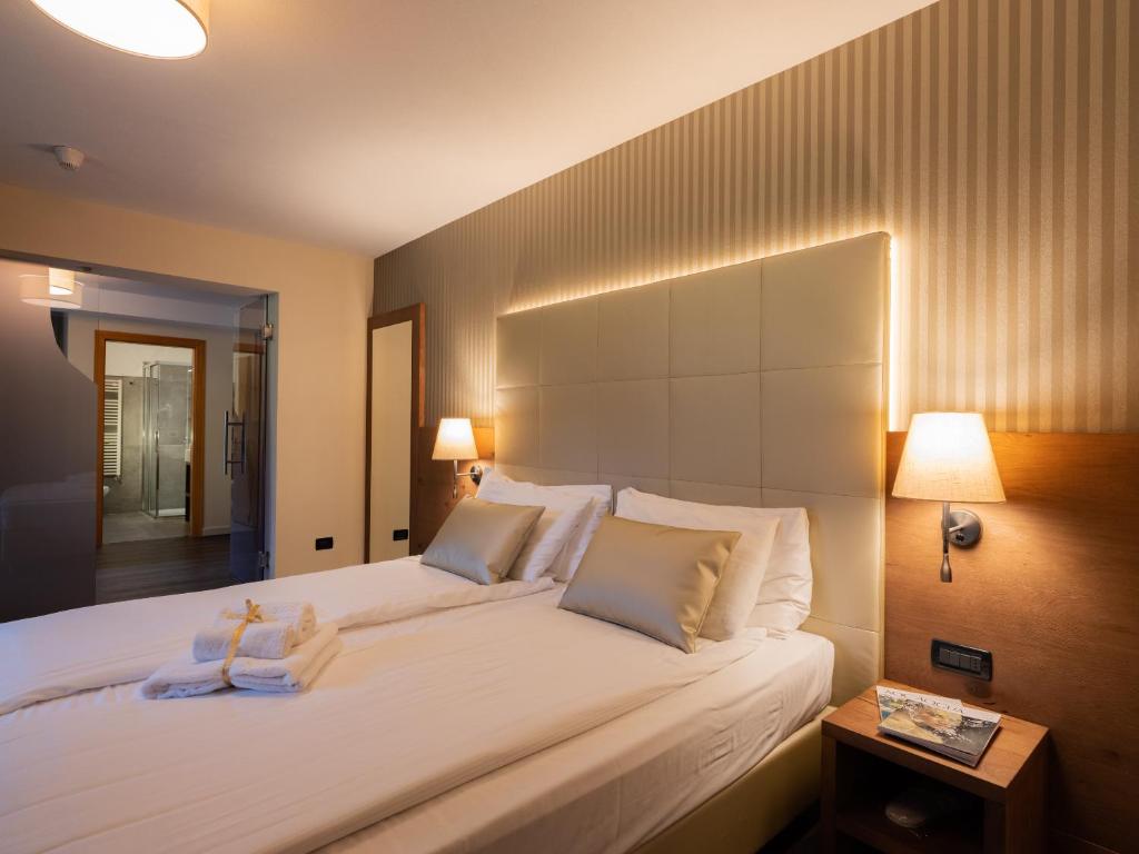 a bedroom with a large white bed with two pillows at X Alp Hotel in Pozza di Fassa
