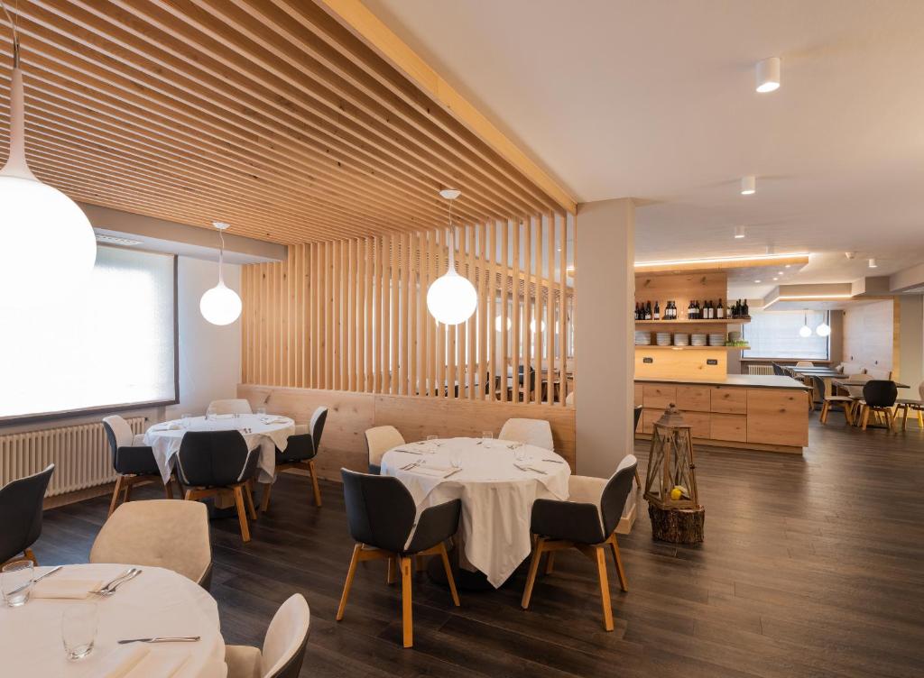 a restaurant with white tables and chairs and a kitchen at X Alp Hotel in Pozza di Fassa