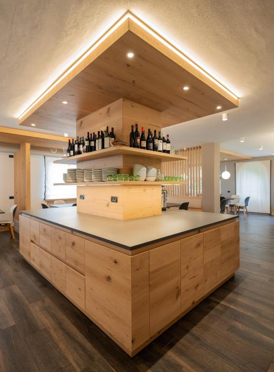 a large kitchen with a counter with bottles of wine at X Alp Hotel in Pozza di Fassa