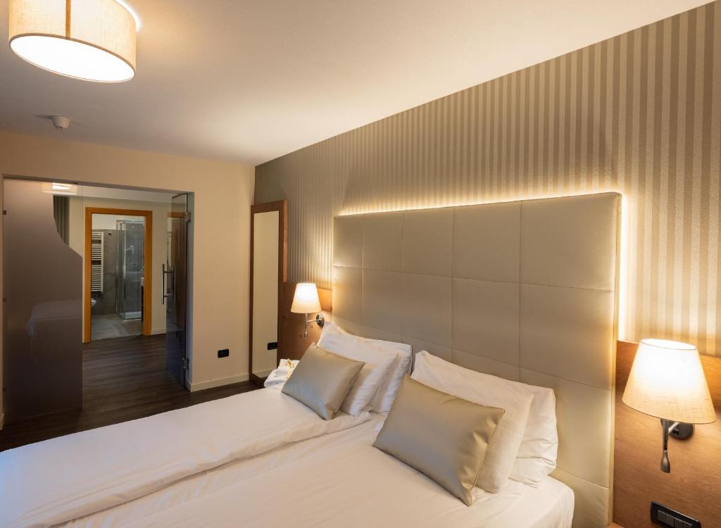 a bedroom with a large white bed with two pillows at X Alp Hotel in Pozza di Fassa