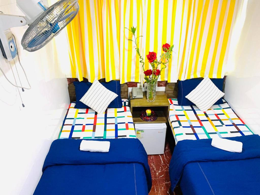 Habitación con 2 camas y cortina amarilla y blanca en Australia Lounge, en Hong Kong