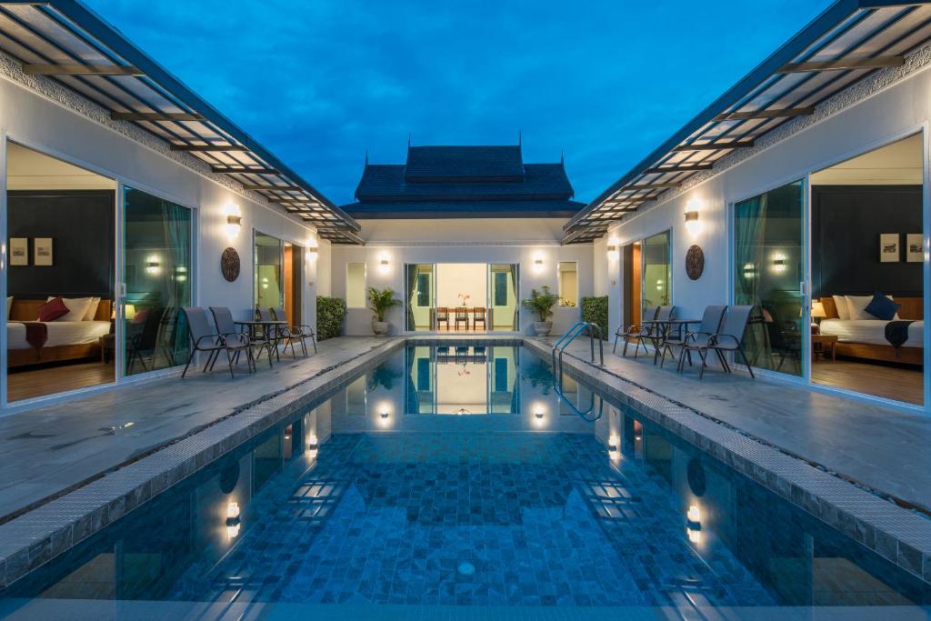 a villa with a swimming pool at night at Phuket La Siesta in Nai Harn Beach