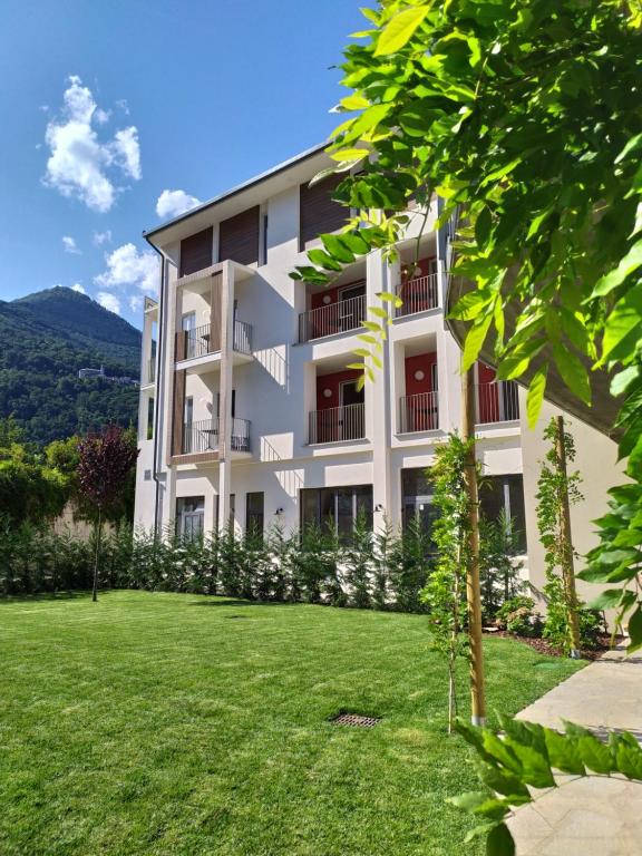 ein weißes Apartmenthaus mit einem grünen Hof in der Unterkunft Hotel Elvezia in Cannobio