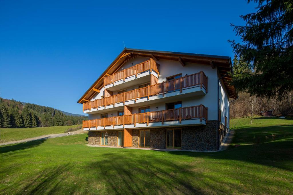 un gran edificio con balcones en un campo verde en Apartmán SOSNA, en Dolný Kubín