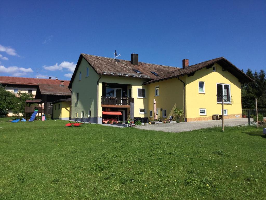 a large yellow and green house with a yard at Haus am Treffenbach in Waldmünchen