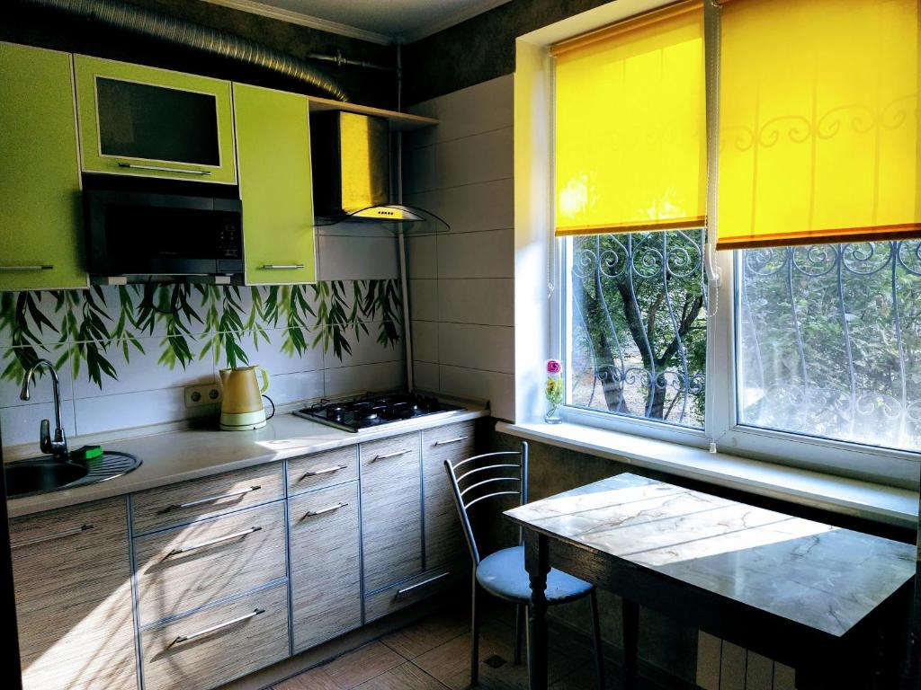 een keuken met gele kasten en een tafel en een raam bij 2 к квартира рядом стадион Металлист м. Спортивная. in Charkov