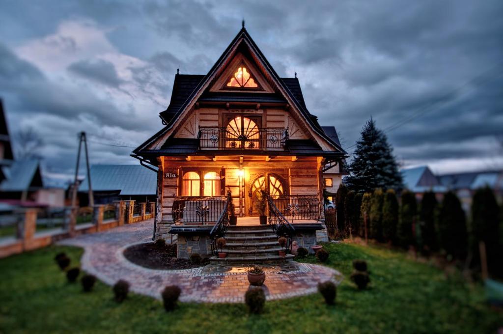 a small wooden house with a lit up window at Willa Topór in Witów