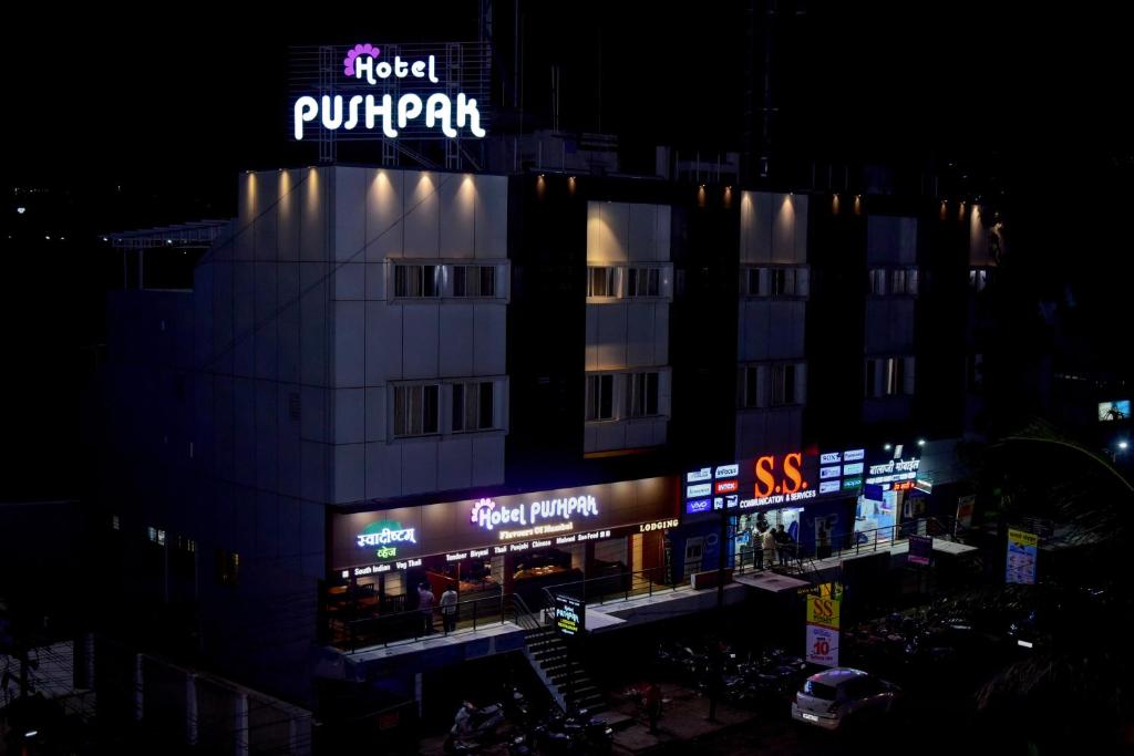a building with a sign on top of it at night at Hotel Pushpak in Satara