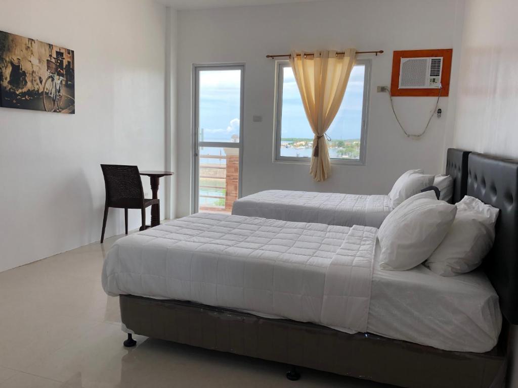a bedroom with two beds and a chair and a window at Arriyus Apartelle in Maya