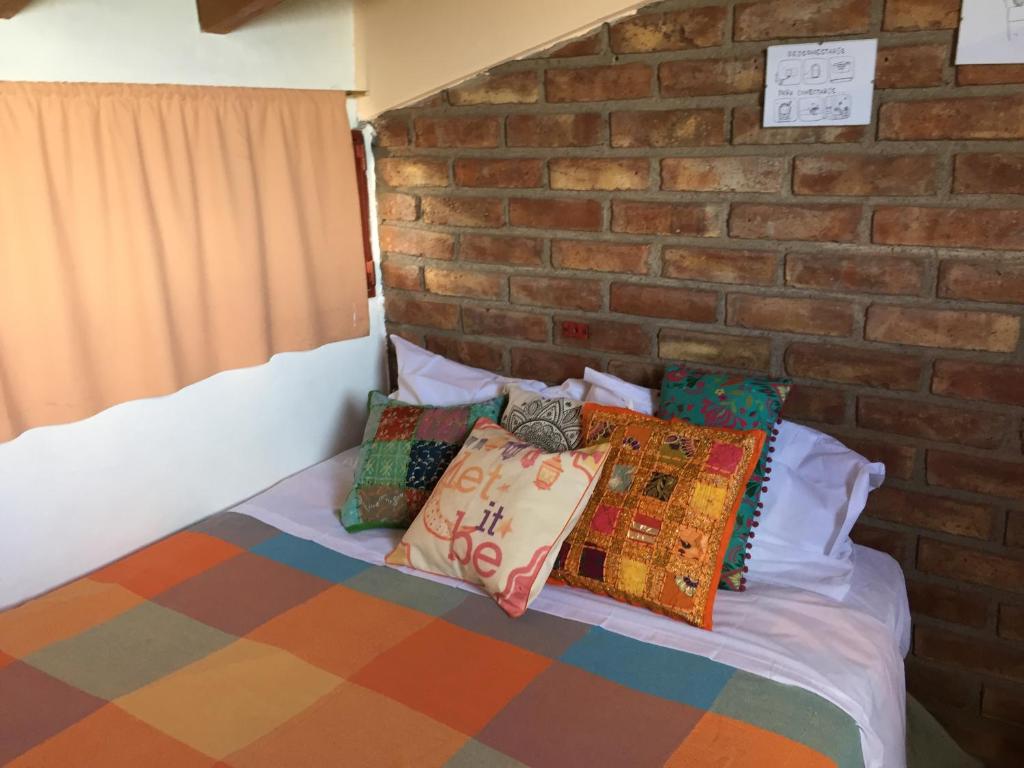 1 cama con almohadas coloridas y pared de ladrillo en Departamento Privado en Gran Mendoza en Godoy Cruz