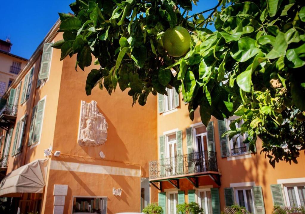 a orange building with a tree in front of it at Hôtel restaurant Oasis in Nice