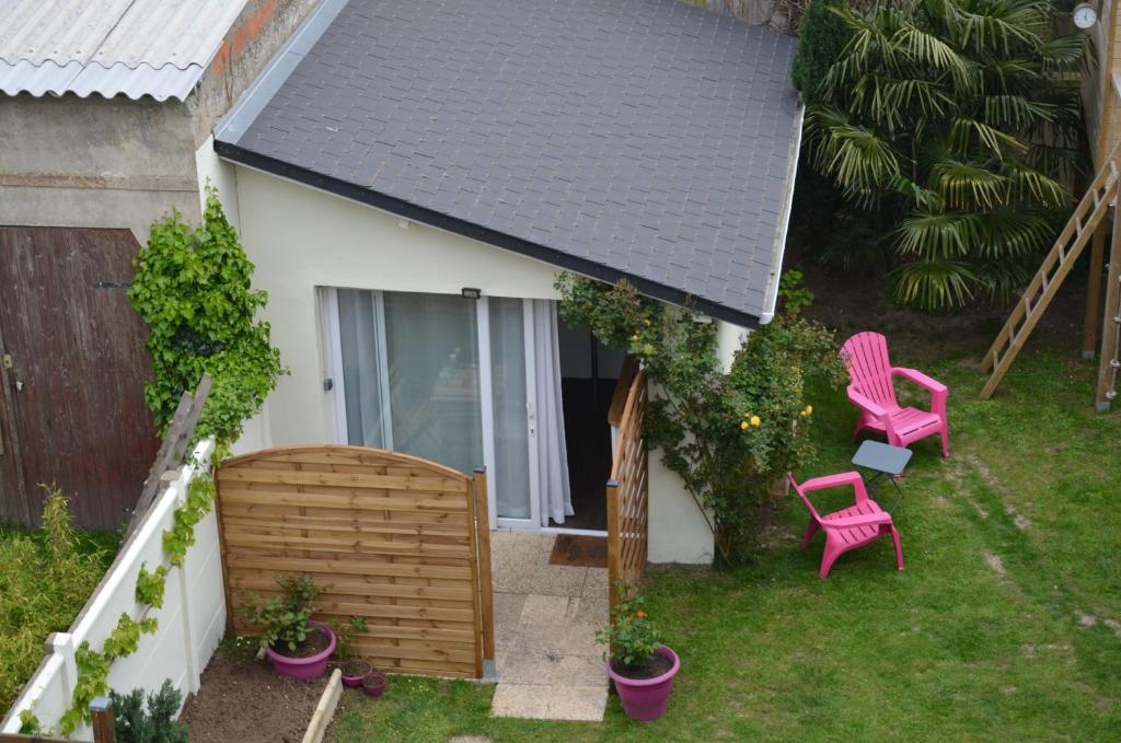 un patio con 2 sillas rosas y una valla en Joli studio au calme dans un jardin privatif, en Ouistreham