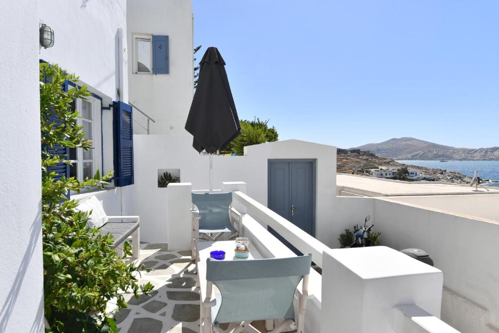 a balcony with white chairs and an umbrella at White Rooms Paros in Naousa