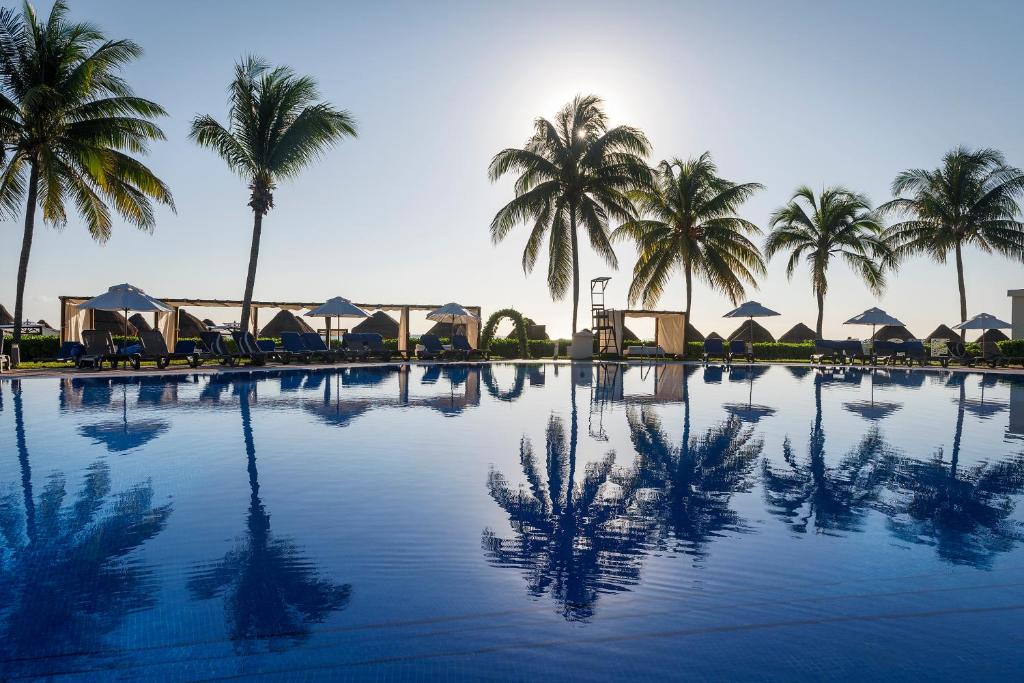 una gran piscina con palmeras y sombrillas en El Beso Adults Only at Ocean Coral & Turquesa All Inclusive en Puerto Morelos