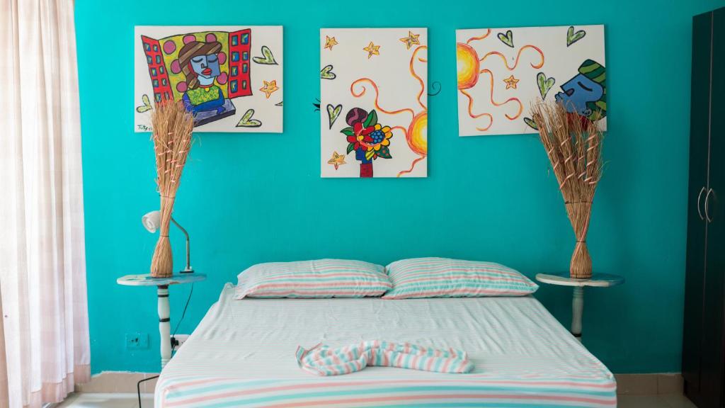 a bedroom with a bed with blue walls and paintings at Apartamento El Nuevo Conquistador in Cartagena de Indias