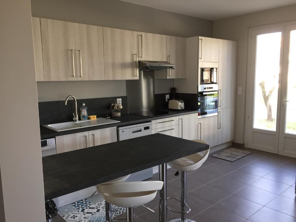 a kitchen with white cabinets and a black counter top at Villa Caramel in Saint-Quentin-la-Poterie