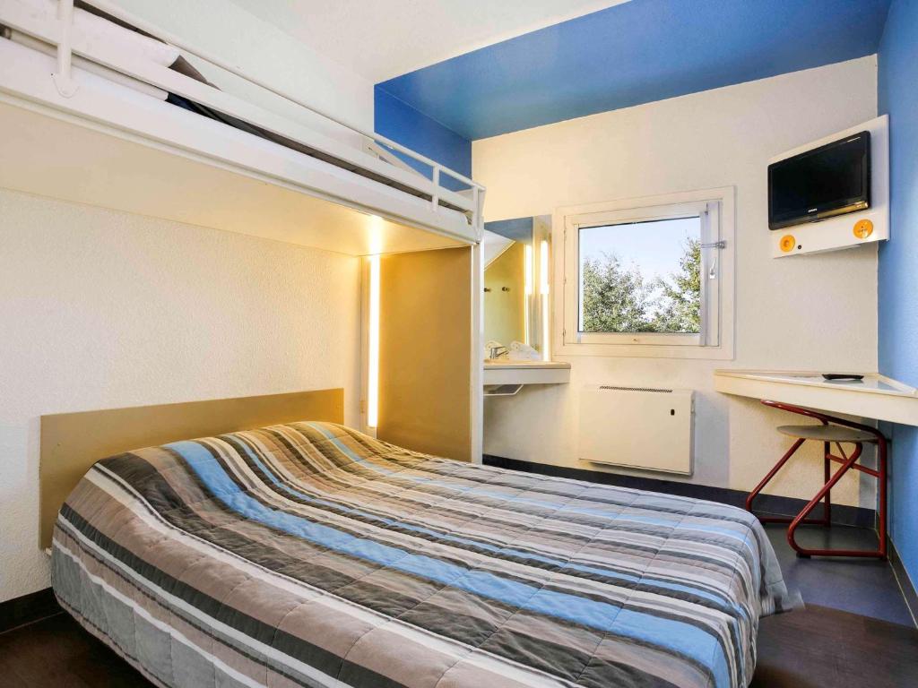 ユサックにあるhotelF1 Brive Ussacのベッドルーム1室(ベッド1台、デスク、窓付)