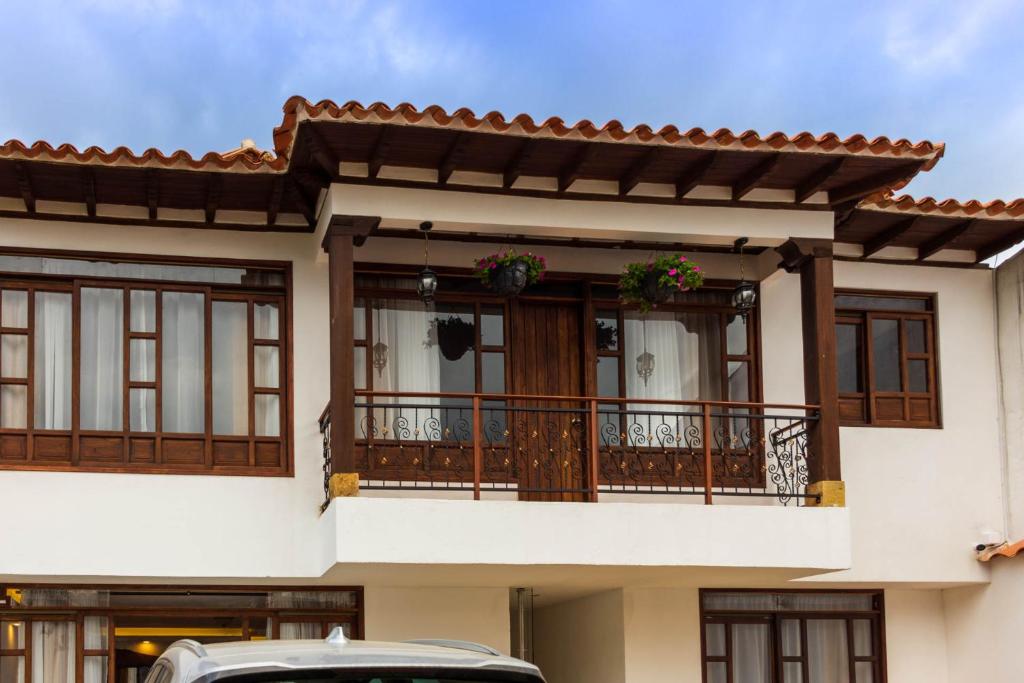 una casa con balcón y un coche aparcado delante en HOTEL ENCANTO COLONIAL, en Villa de Leyva