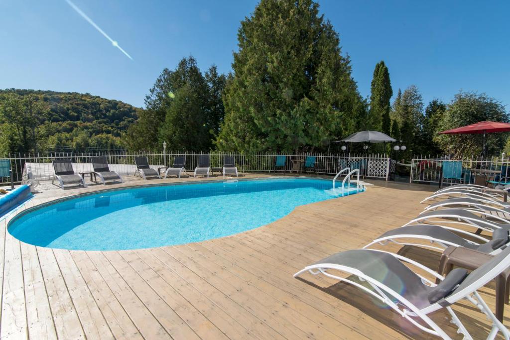 a swimming pool with lounge chairs and an umbrella at Auberge Hotel Spa Watel in Sainte-Agathe-des-Monts