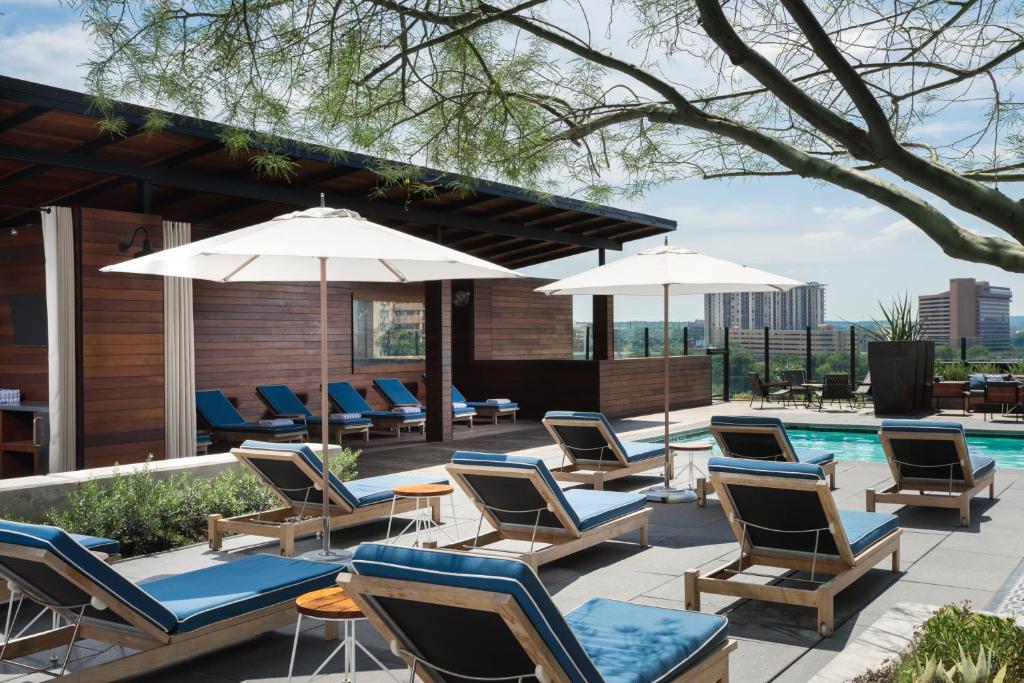 a group of chairs and umbrellas next to a pool at Hotel Van Zandt in Austin