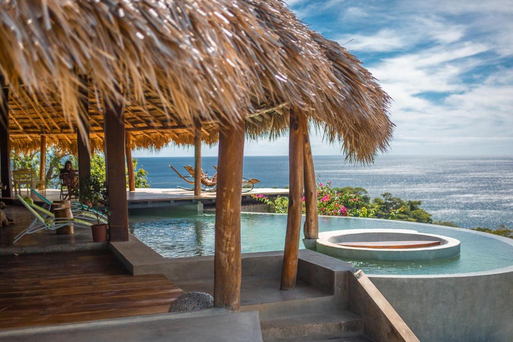 a resort with a pool and a straw umbrella at Hush Maderas in San Juan del Sur