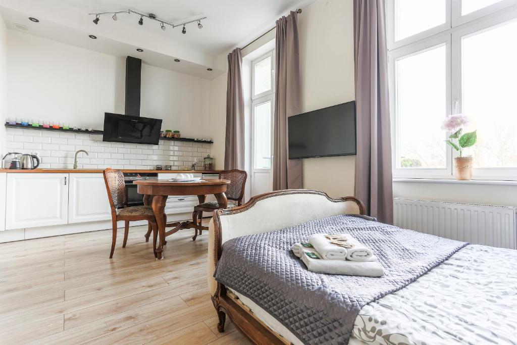 Un dormitorio con una cama y una cocina con una mesa. en SunHouse Apartment, en Toruń
