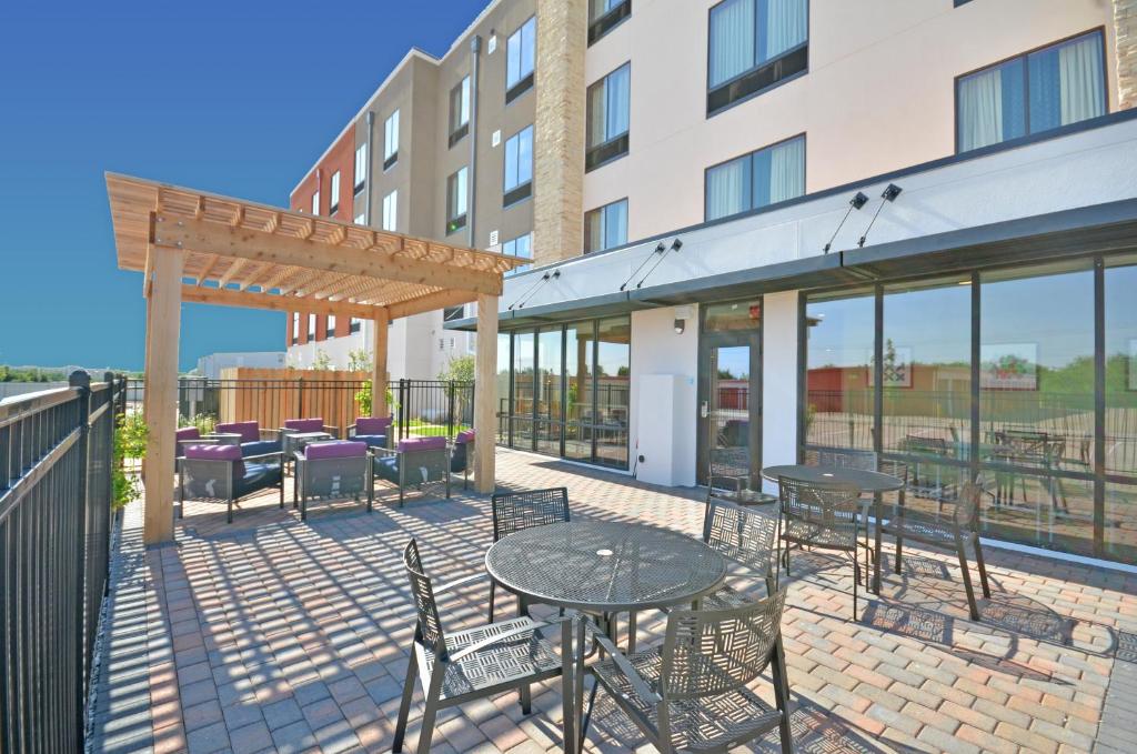 a patio with tables and chairs in front of a building at Holiday Inn Express & Suites Oklahoma City Mid - Arpt Area by IHG in Oklahoma City