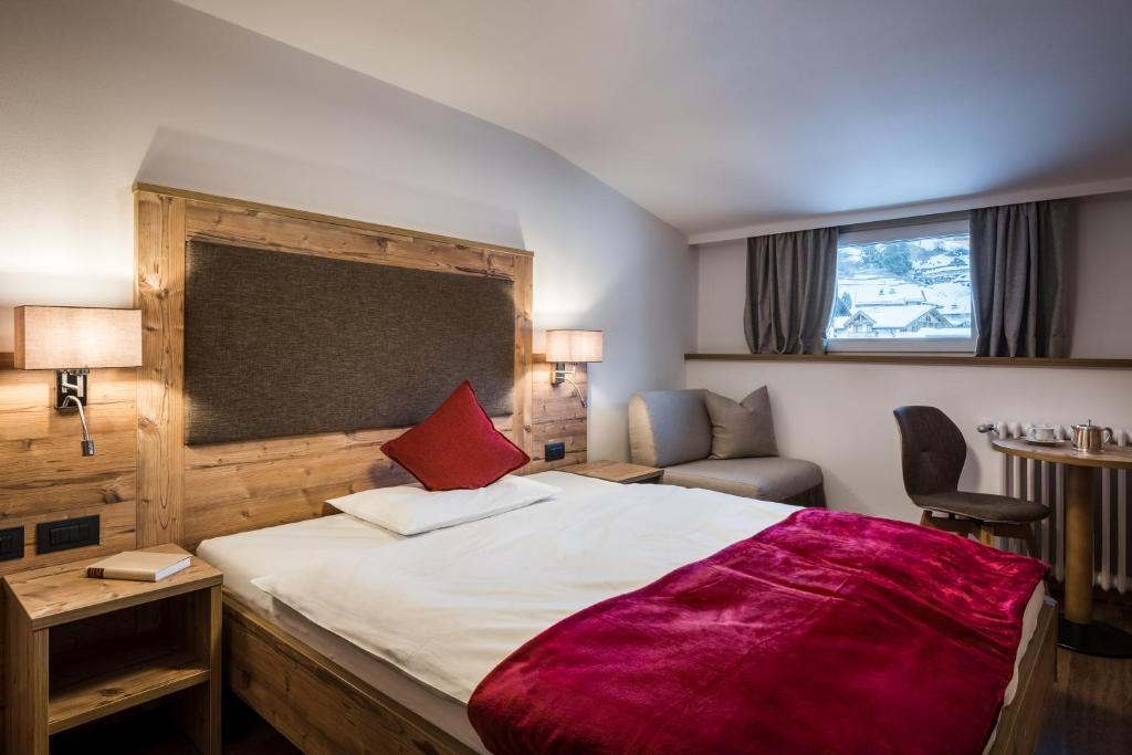 um quarto com uma cama grande e um cobertor vermelho em Charme Hotel Uridl em Santa Cristina in Val Gardena