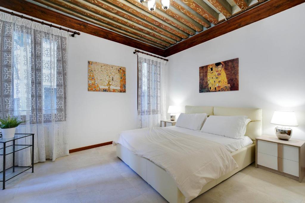 ein weißes Schlafzimmer mit einem großen Bett und Fenstern in der Unterkunft Ca' Rialto in Venedig