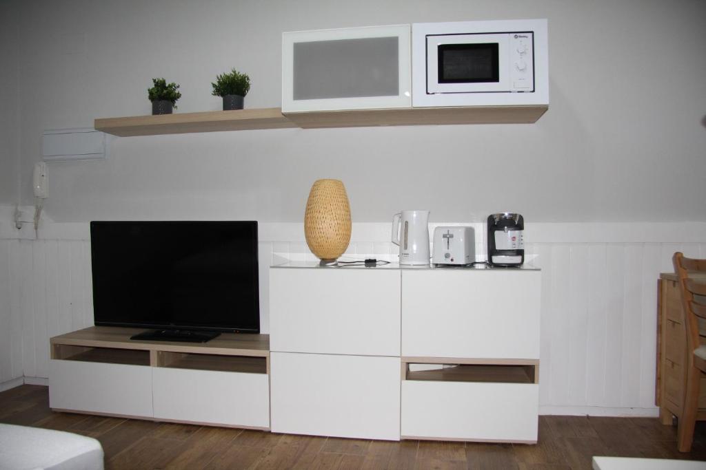 a white entertainment center with a tv and a microwave at Vielha Centro Estudio in Vielha