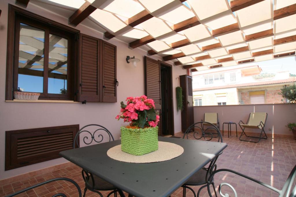 una mesa con un jarrón de flores en un patio en Casa Levante, en Oliveri