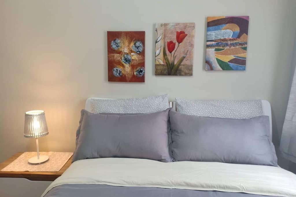 1 dormitorio con 1 cama con 3 cuadros en la pared en 2BR Apartment - Pasig Stay, en Manila