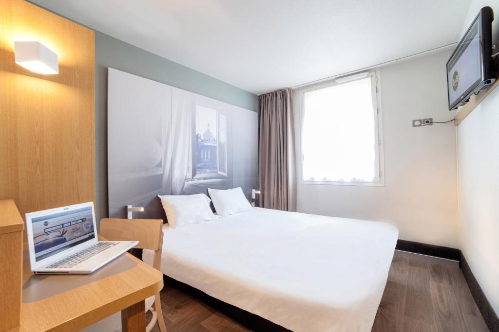 ein Hotelzimmer mit einem Bett und einem Laptop auf dem Schreibtisch in der Unterkunft B&B HOTEL Dunkerque Centre Gare in Dunkerque