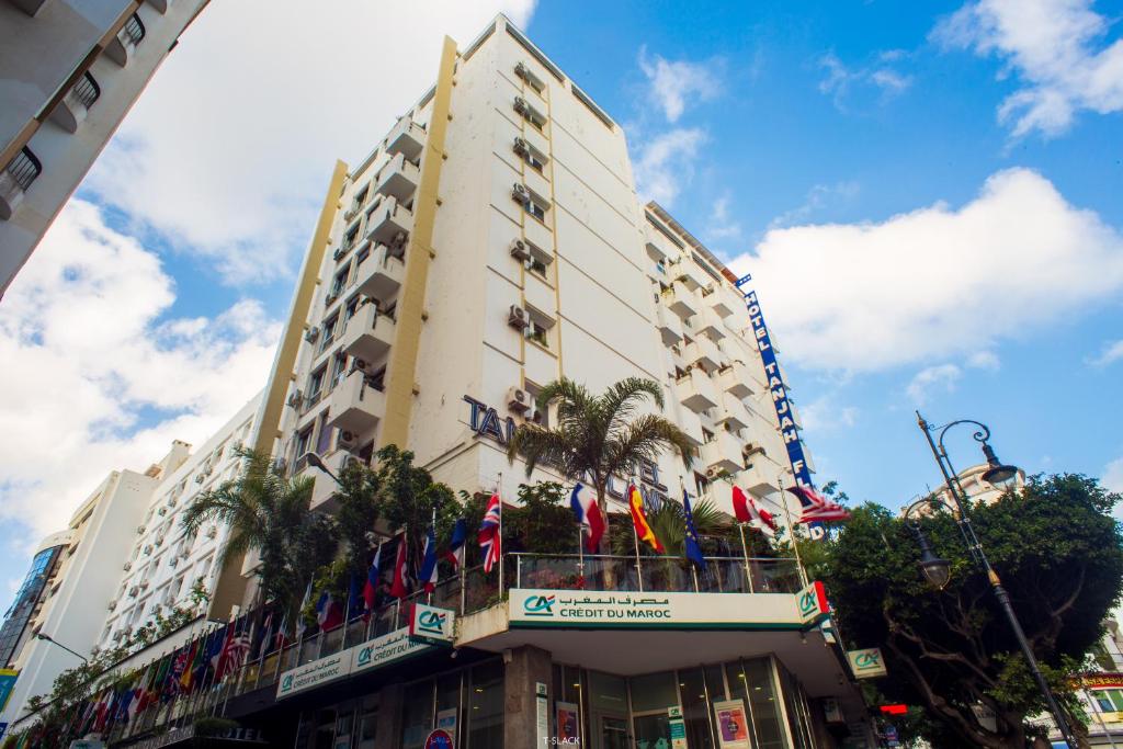 a tall building with flags on a balcony at Hôtel Tanjah Flandria in Tangier