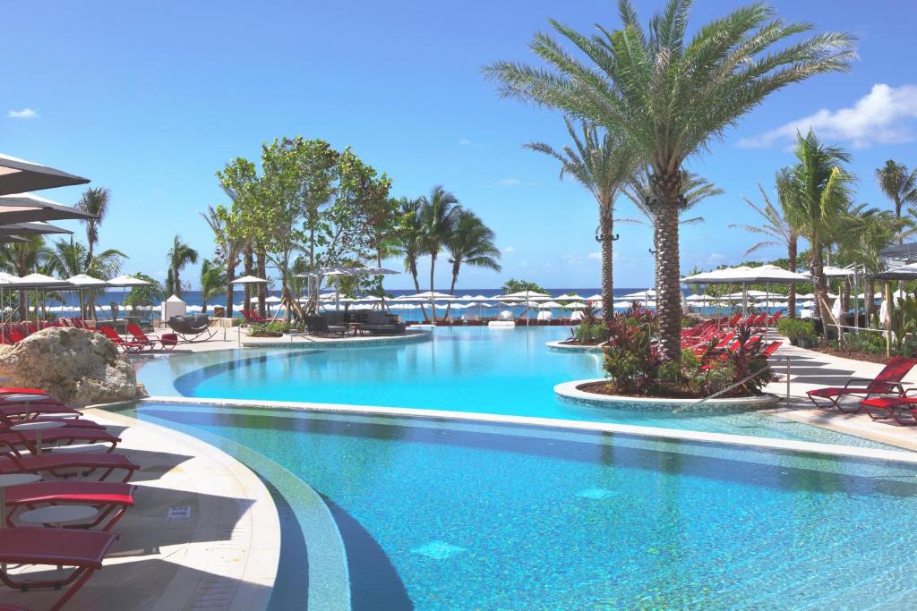 a swimming pool at a resort with chairs and palm trees at Kimpton Seafire Resort + Spa, an IHG Hotel in West Bay